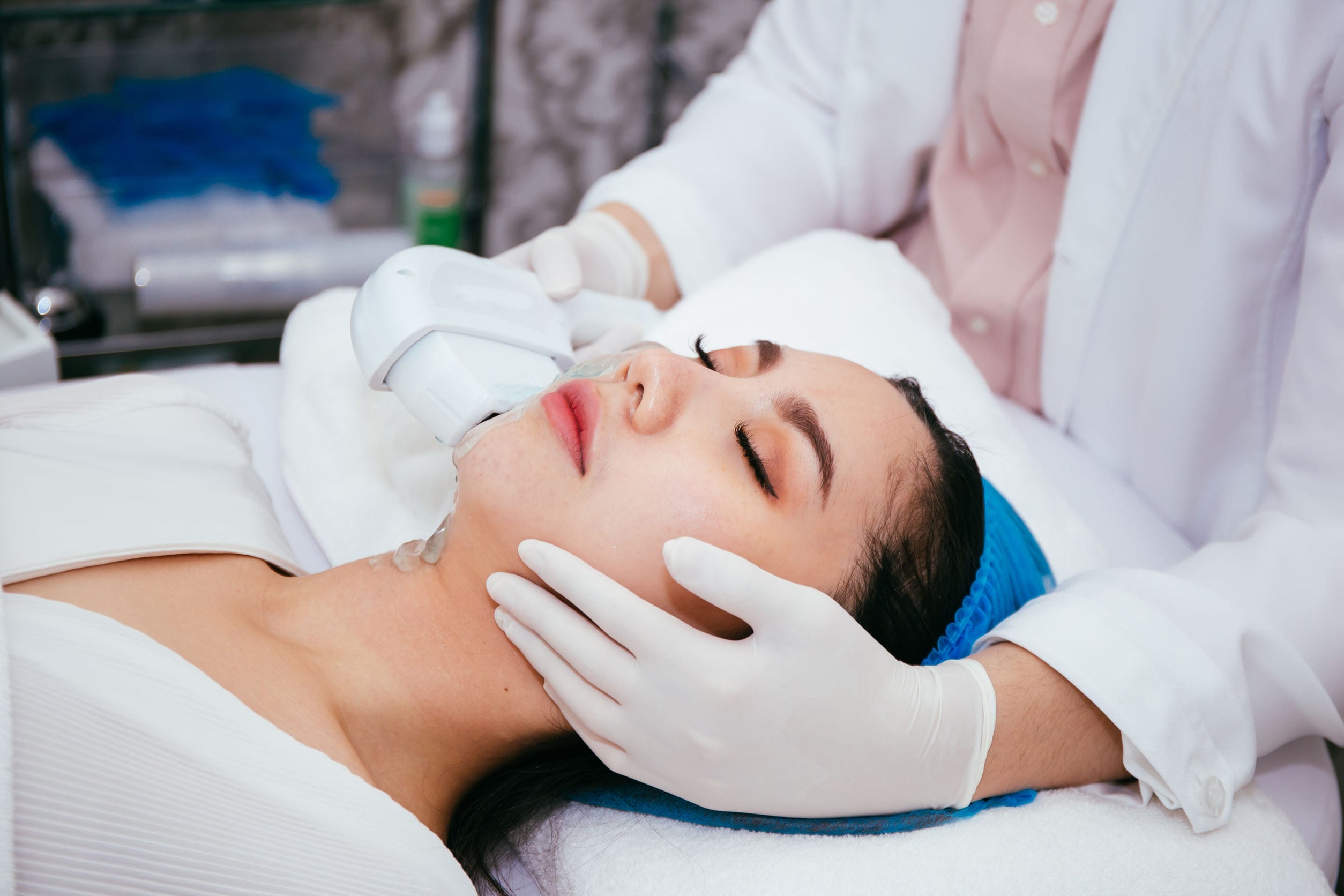 Young woman getting IPL and laser treatment by beautician at beauty clinic